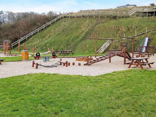 a playground with wooden benches and a slide at 5 star holiday home in Lemvig-By Traum in Lemvig