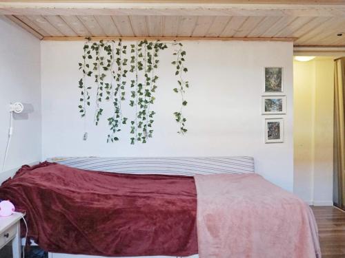 ein Schlafzimmer mit einem Bett mit einer Pflanze an der Wand in der Unterkunft Holiday home ENSKEDE in Stockholm