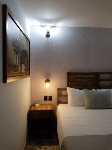 a bedroom with a bed and a night stand with a lamp at Añoranza Hotel Boutique in Ciudad Hidalgo
