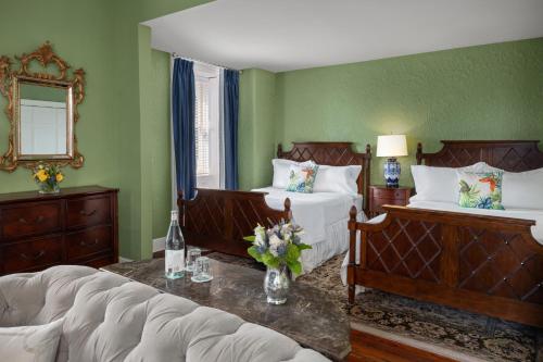 a bedroom with two beds and a couch and a mirror at Hamilton Turner Inn in Savannah
