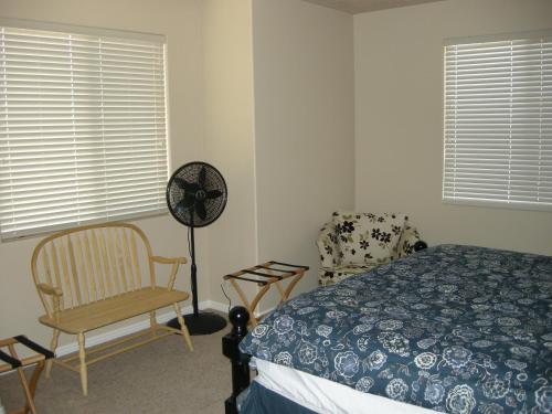 ein Schlafzimmer mit einem Bett, einem Stuhl und einem Ventilator in der Unterkunft Nevada Mesquite Vacation Rentals in Mesquite