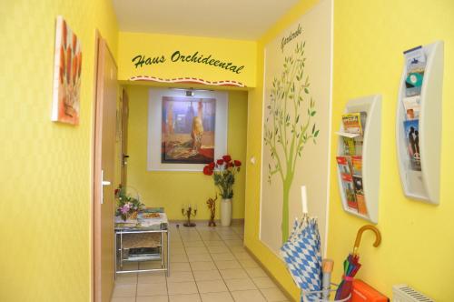 a hallway with a yellow wall with a pharmacyacistacistacistacistacist at Hotel Haus Orchideental Jena in Jena