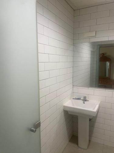 a white bathroom with a sink and a mirror at Hanra guesthouse in Jeju