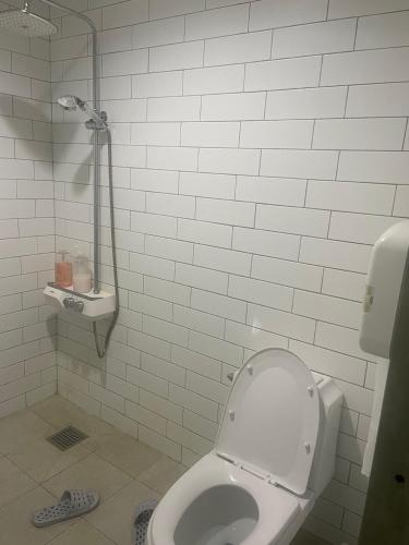a white bathroom with a toilet and a shower at Hanra guesthouse in Jeju