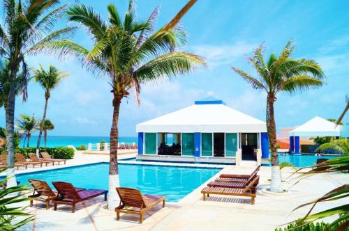 een zwembad van het resort met palmbomen en de oceaan bij Solymar hermoso apartamento in Cancun