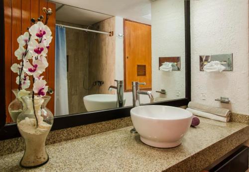 een badkamer met een wastafel en een vaas met bloemen op een aanrecht bij Solymar hermoso apartamento in Cancun