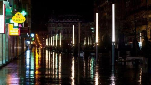 a wet city street at night with lights at Blue light ultracentral in Craiova