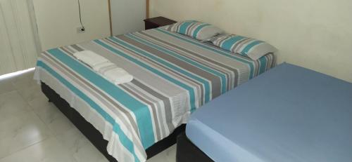 Cama con sábanas y almohadas de rayas azules y blancas en Casa central, en Santa Marta