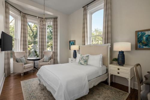 een witte slaapkamer met een bed en een tafel en stoelen bij Hamilton Turner Inn in Savannah