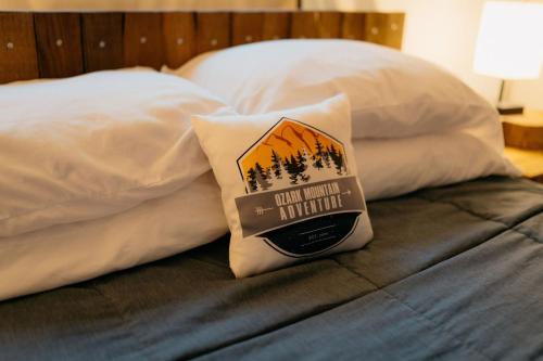 Una almohada con una señal sentada en una cama en Treehouse Cozy Glamping Site en Branson