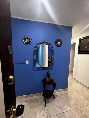 a room with a blue wall with a table and a mirror at hermoso y super acojedor apartamento in Bogotá
