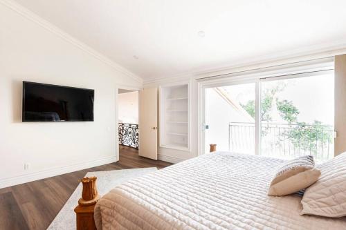 a white bedroom with a bed and a large window at Calabasas Villa Lake View Home in Calabasas