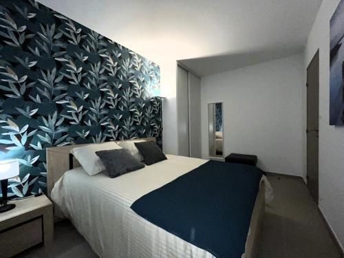 a bedroom with a large bed with a blue wall at Confortable Appartement près d'AVIGNON in Le Pontet