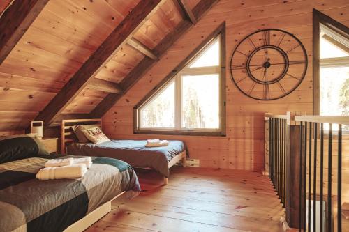 a room with two beds and a large clock on the wall at Le Refuge in Saint-Henri-de-Taillon