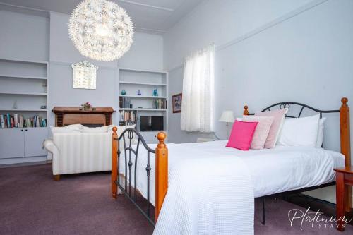 a bedroom with a large bed and a chandelier at Victorian Goldfields Cottage in Ballarat