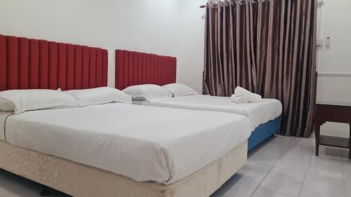 two beds in a room with red curtains at Anjung KLIA House 01 With Neflix & Airport Shuttle in Banting