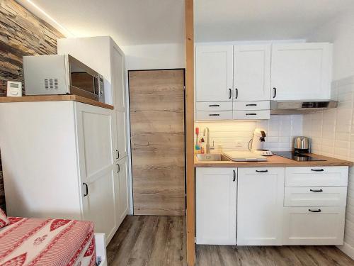 Elle comprend une petite cuisine avec des placards blancs et une porte en bois. dans l'établissement Studio rénové, 6 pers · Pieds des pistes · Balcon sud - FR-1-275-204, à La Rosière