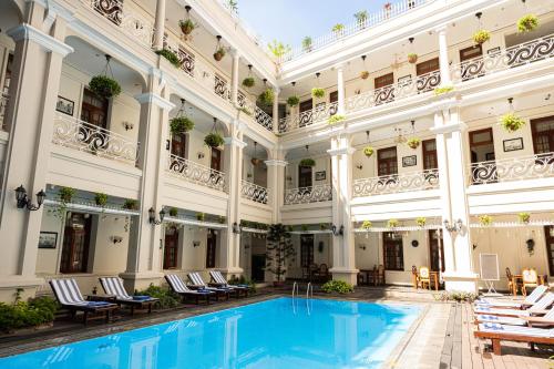 a pool in the courtyard of a building with chairs at Hotel Grand Saigon in Ho Chi Minh City