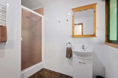 een witte badkamer met een wastafel en een spiegel bij Diamond Forest Farm Stay in Manjimup
