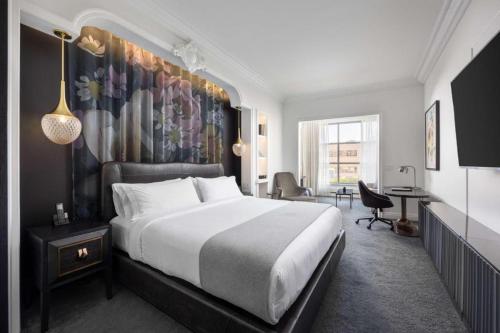 a bedroom with a large bed with a painting on the wall at Daxton Hotel Birmingham, Curio Collection by Hilton in Birmingham