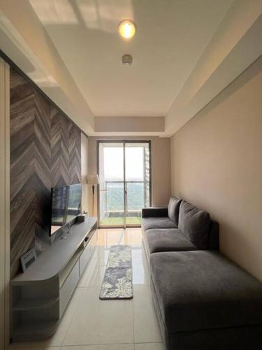 sala de estar con sofá y TV de pantalla plana en Elegant Mangrove Haven Luxe 1BR at Gold Coast PIK, en Yakarta
