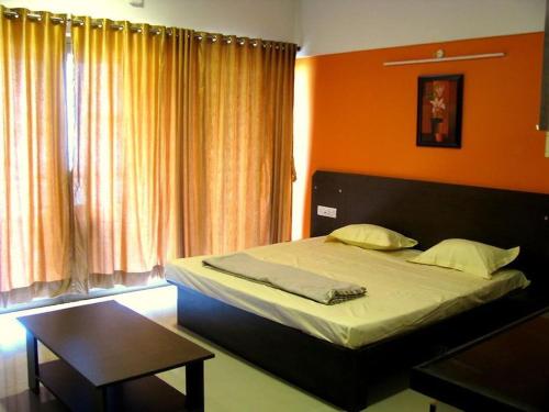 a bedroom with a large bed with an orange wall at Infinity Lake View Studio in Lavasa