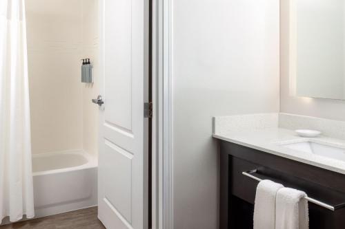 a white bathroom with a sink and a tub at Residence Inn Providence Coventry in West Greenwich