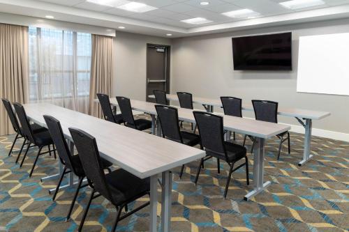 a conference room with tables and chairs and a screen at Residence Inn Providence Coventry in West Greenwich