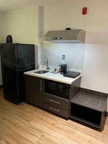 a kitchen with a sink and a black refrigerator at Studio 6 Suites Stockton, CA Waterfront in Stockton