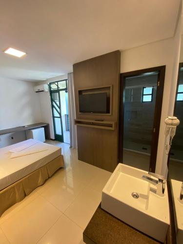a bedroom with a bed and a sink and a tv at Spazio Vital Apartments in Florianópolis