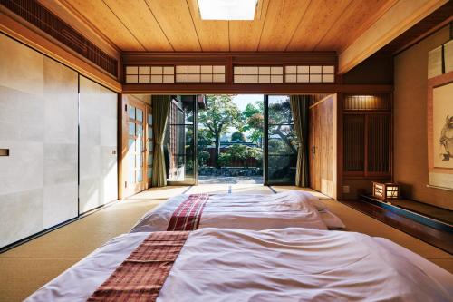 un grande letto in una stanza con una grande finestra di 町住客室 秩父宿 a Chichibu