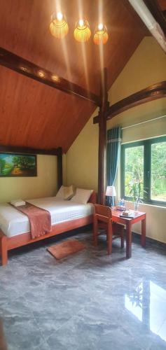 a bedroom with two beds and a table and windows at Tam's Homestay in Phong Nha