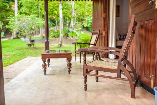two rocking chairs and a table on a porch at Araliya Gardens Hotel in Hikkaduwa