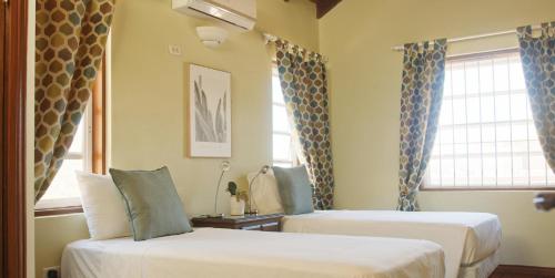 2 Betten in einem Zimmer mit 2 Fenstern in der Unterkunft Trilogy Villas in English Harbour Town