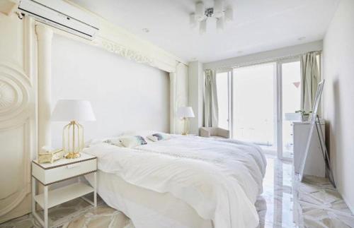 a white bedroom with a large bed and a window at Reimi Mondo501 in Tokyo