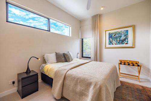 a bedroom with a large bed and two windows at Cooee -Brand new with private pool 350m to beach! in Byron Bay