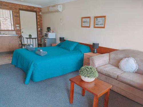 a bedroom with a blue bed and a couch at Hills of Gold Motel at Nundle in Nundle