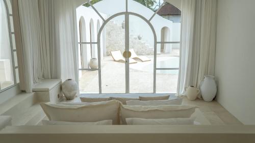 a living room with white furniture and a large window at MAJA Canggu in Canggu