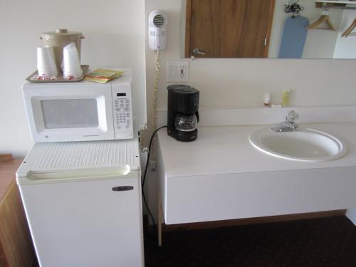 a kitchen with a microwave and a sink at Bishops Country Inn Motel in Jackman