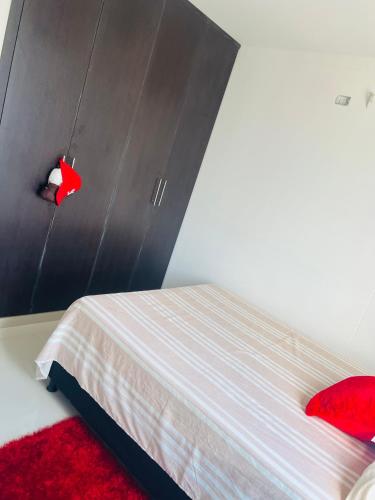 a bedroom with a bed with a headboard and red rug at Habitación confortable in Valledupar