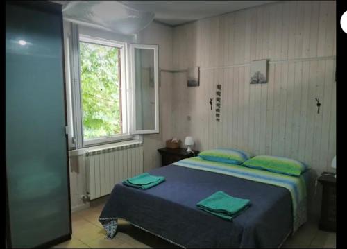 Un dormitorio con una cama con almohadas verdes y una ventana en nel cuore della città, en Urbania
