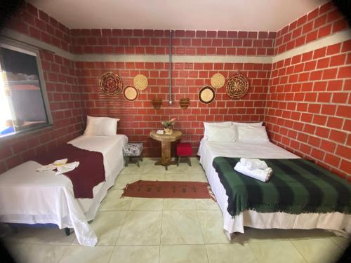 um quarto com duas camas e uma parede de tijolos em POUSADA ALLES em Santo Amaro