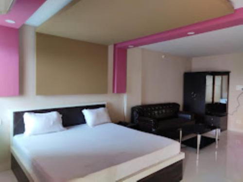 een slaapkamer met een groot bed en een zwarte stoel bij Hotel Kanha Shyam Madhubani in Madhubani