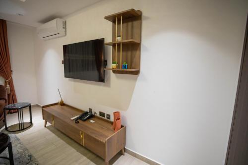 a living room with a table and a tv on a wall at Veronique Heights in Kumasi