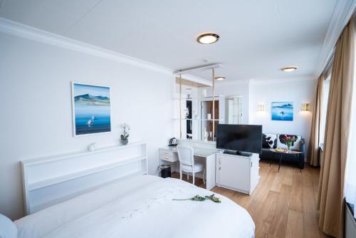 Cette chambre blanche comprend un lit et un bureau avec un ordinateur. dans l'établissement Hotel Keflavik by Reykjavik Keflavik Airport, à Keflavík