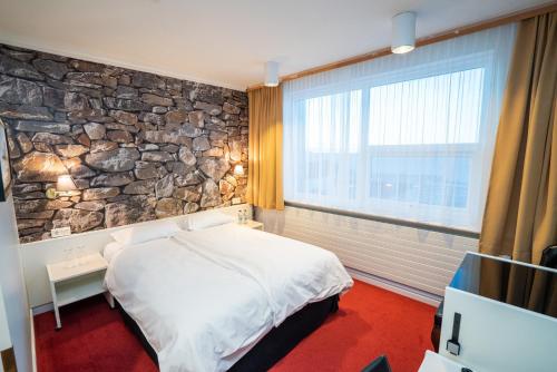 a bedroom with a stone wall with a bed and a window at Hotel Keflavik by Reykjavik Keflavik Airport in Keflavík