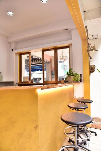 a bar with two stools in a room with windows at 山露露品茶 70年代老房子 二樓背包 4-5樓合併 六人包層 Te en Te' Guesthouse in Tainan