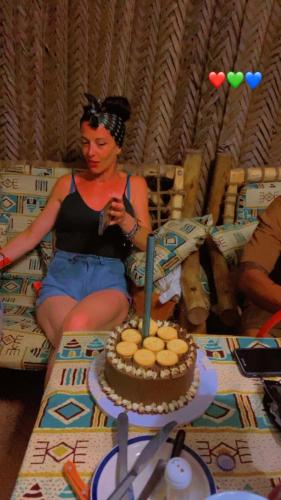 a woman sitting on the floor next to a table with a cake at PALM - 2minutes walk to the beach in Nungwi