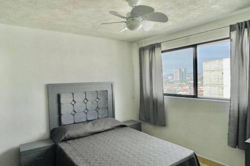 una camera con letto, ventilatore a soffitto e finestra di Hermoso Departamento Céntrico, Facturamos a Guadalajara