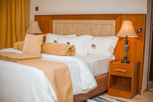 Schlafzimmer mit einem Bett mit weißer Bettwäsche und Kissen in der Unterkunft LEYSHOF HOTEL in Mwanza